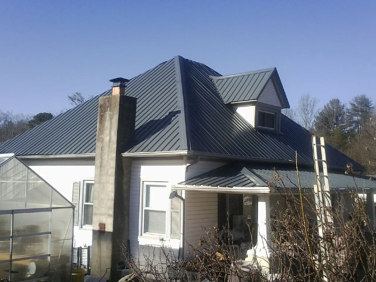 Dark blue standing seam metal roof on a white farmhouse with dormer — Slate & Tile Roof Repair by Roofing Brothers in Carthage